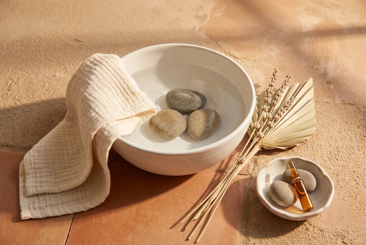 A minimal arrangement of water, smooth stones, and a washcloth representing a simplified skincare routine