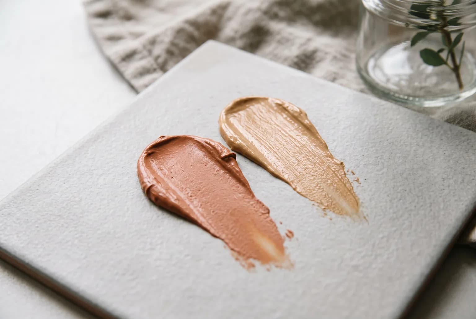 Close-up swatches of cream bronzer on ceramic tile