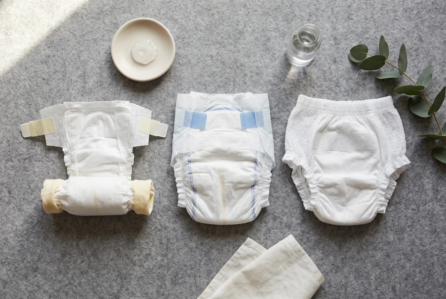 Three diaper formats laid side-by-side on grey felt: newborn, taped, and pull-up