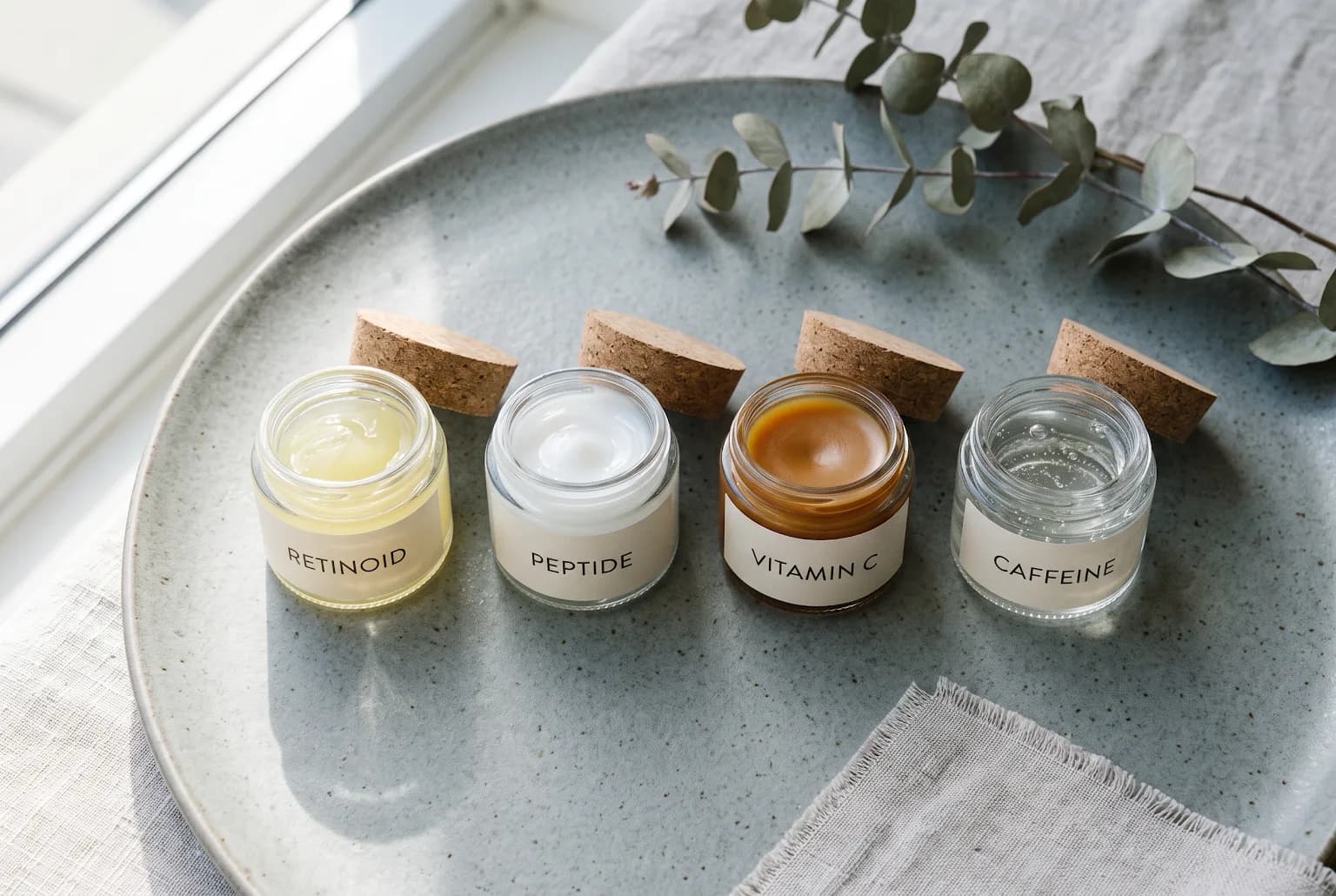 Four small pots showing different eye cream textures arranged in a row