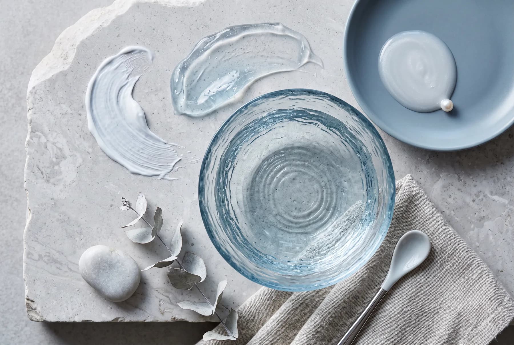 Clear gel and cream textures arranged with water ripples to illustrate hydration-focused eye-care formats