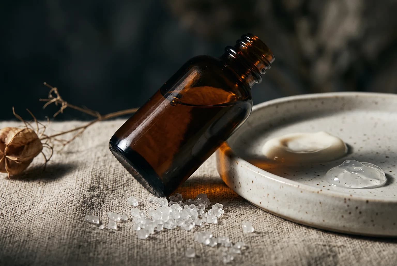 Amber serum bottle on ceramic tray with hyaluronic crystals