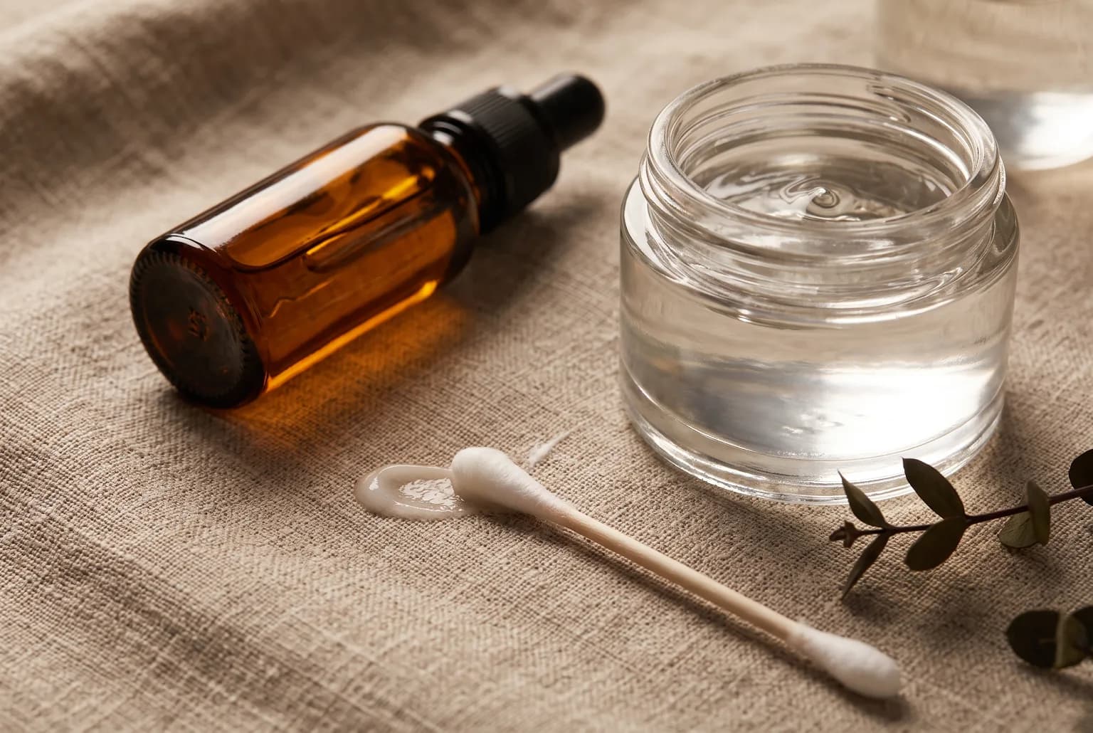 Amber bottle of facial oil and a jar showing a silicone-like sheen to represent occlusives