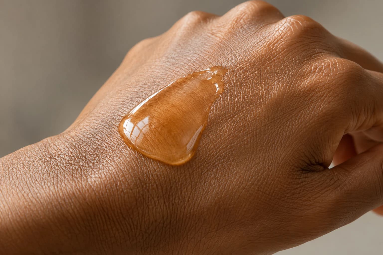 Glossy amber-colored swatch spread across the back of a hand.