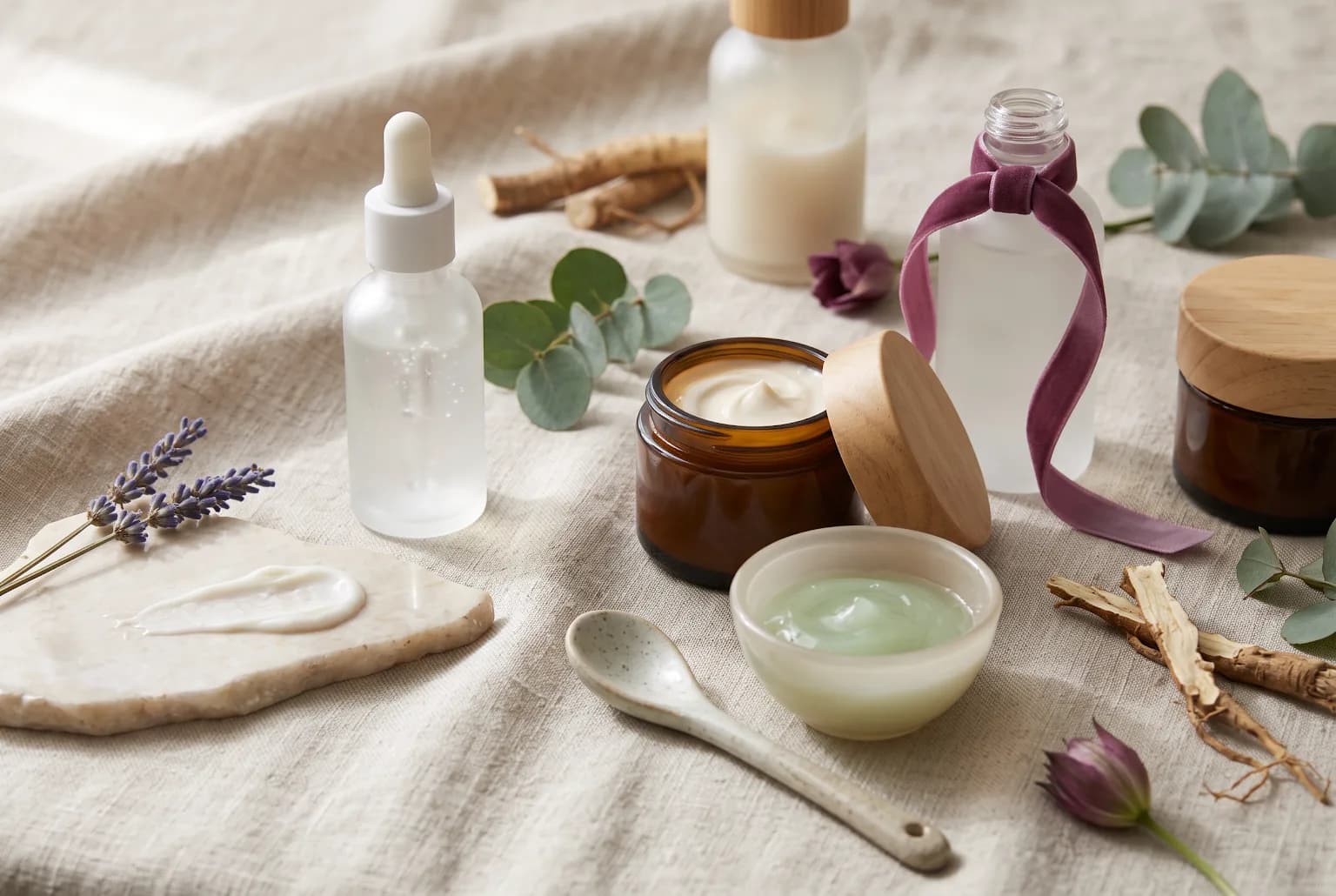 Still life of acne-active skincare items: dropper bottle, white tube, bowl of light powder on stone slab