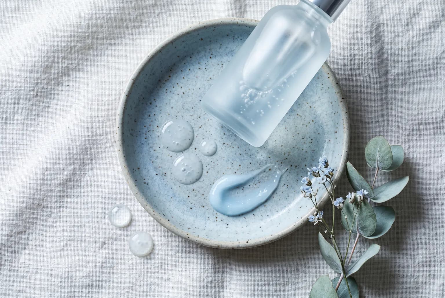 Close-up of a retinol serum bottle beside a ceramic dish with droplets