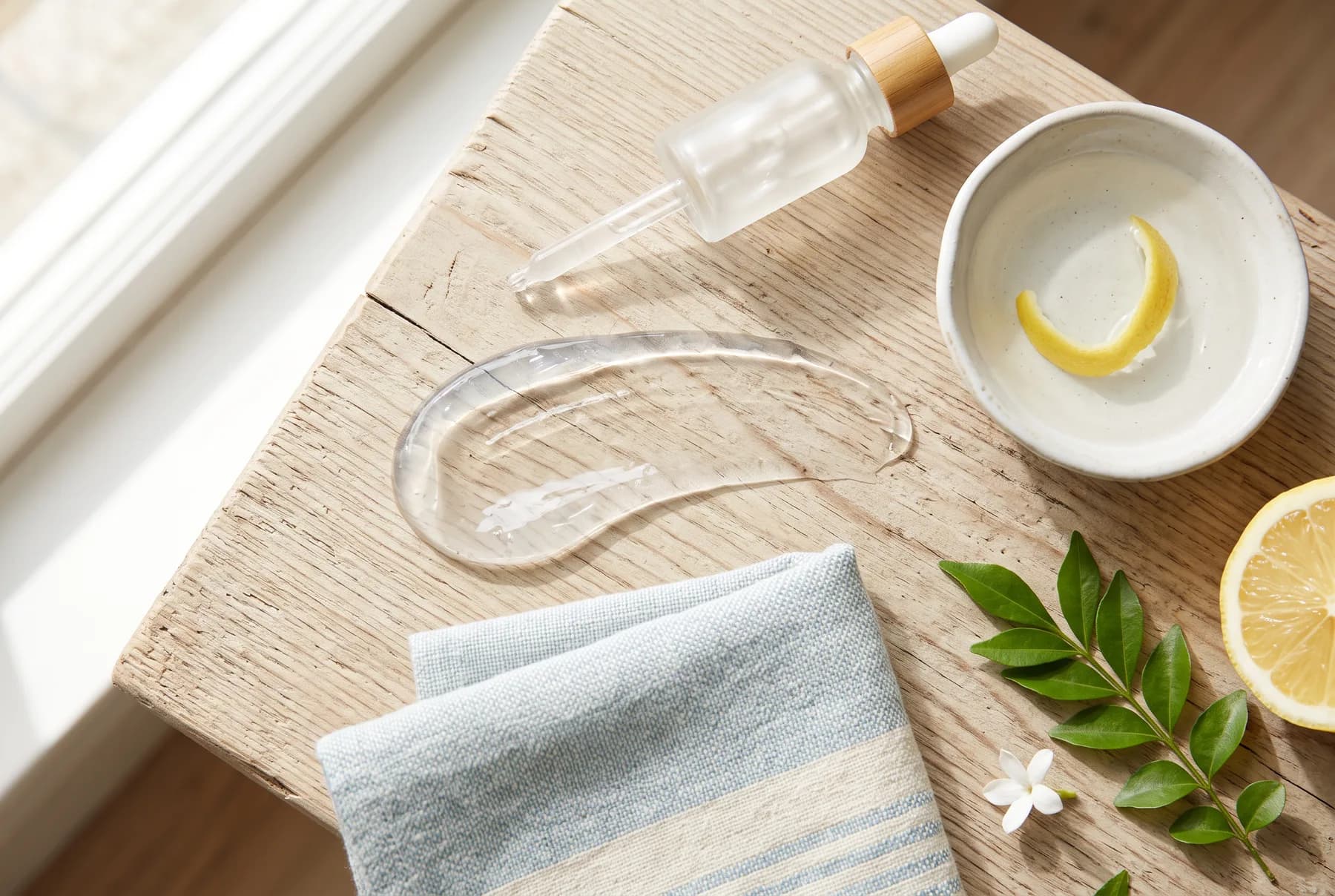 Morning skincare ritual with a serum texture, citrus peel, and linen