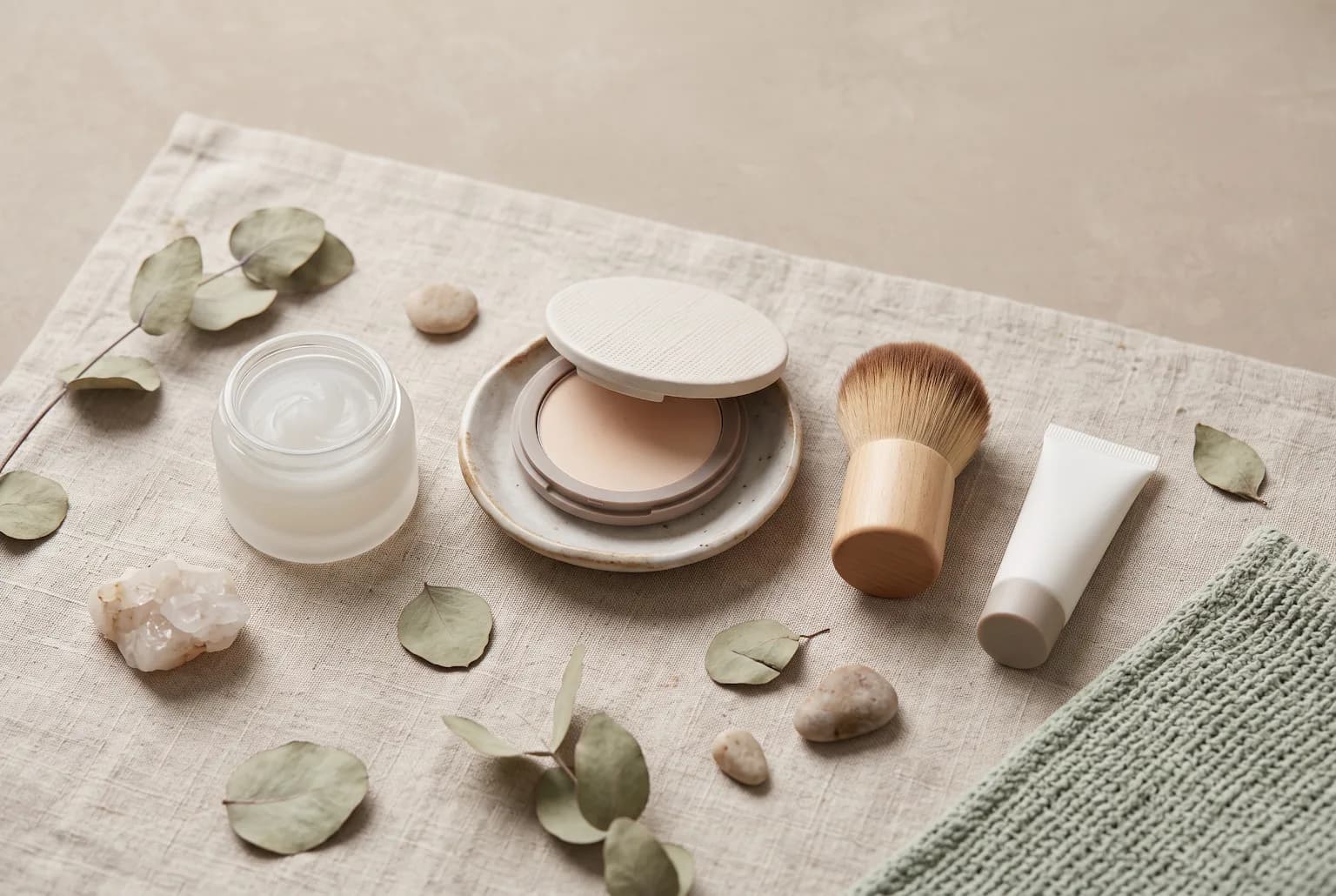 Mattifying primer, translucent powder, brush and small sunscreen tube flatlay