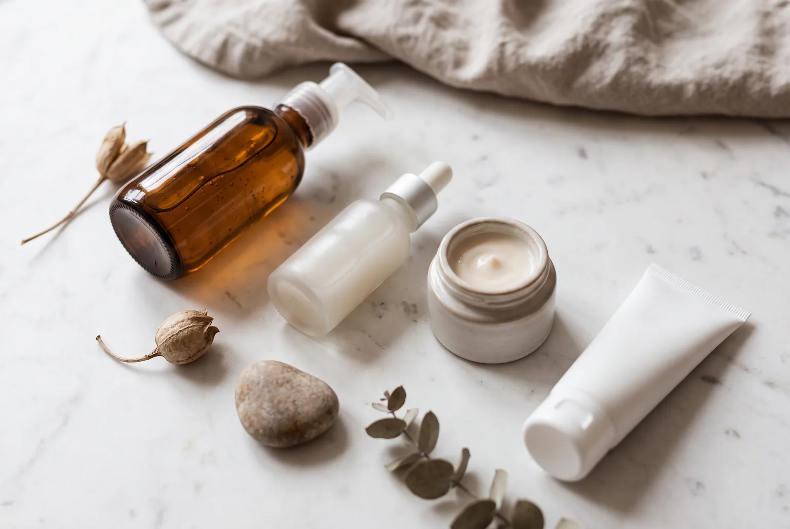 Flat lay of cleanser, serum, moisturizer and sunscreen on marble