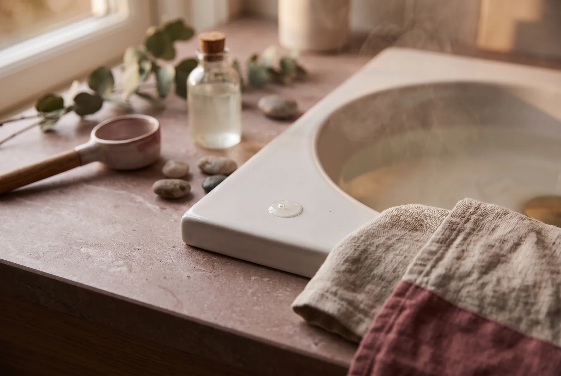 Hands gently pressing hydrating serum into damp facial skin at a sink