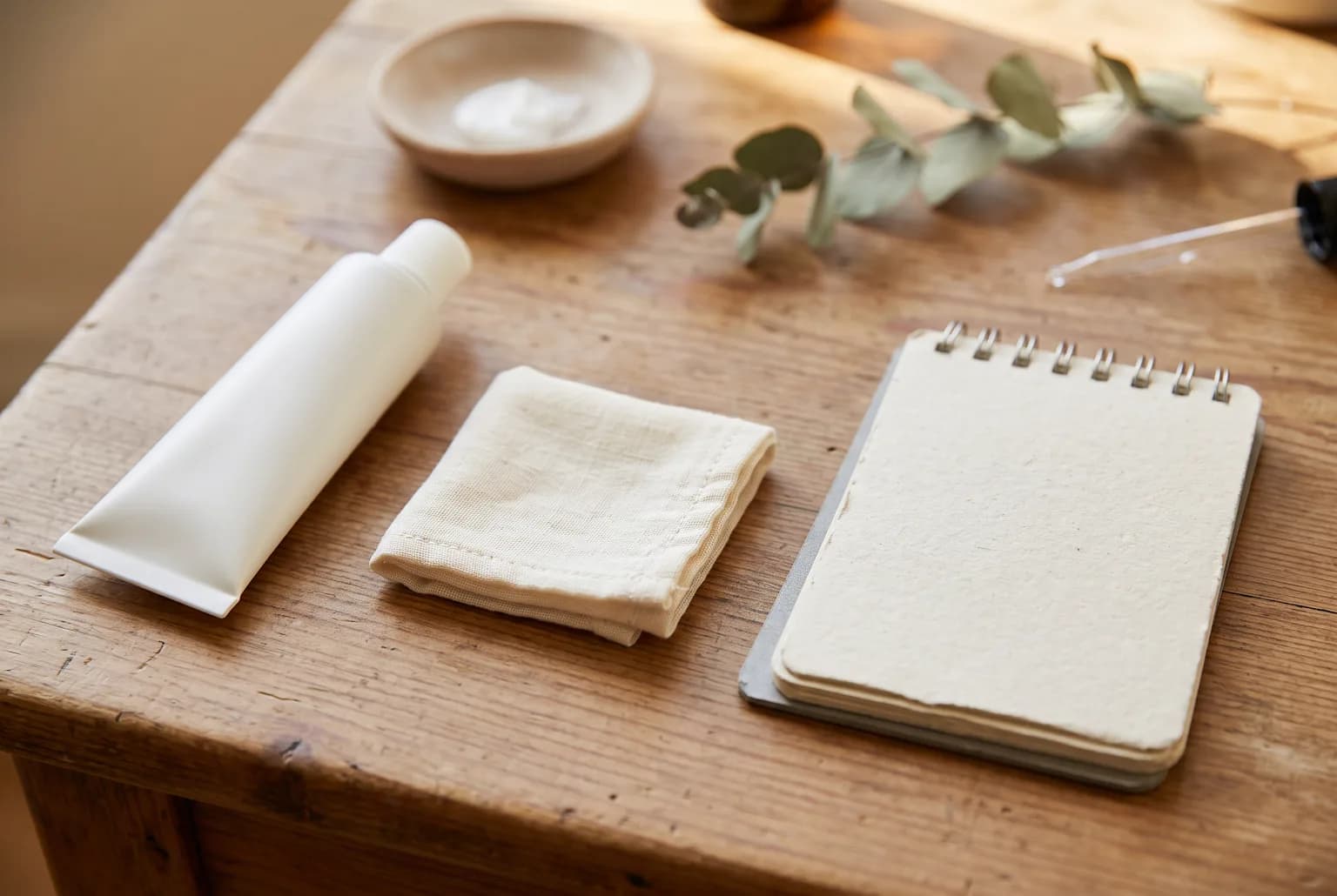 Sunscreen tube beside patch-test cotton square and notebook on wood