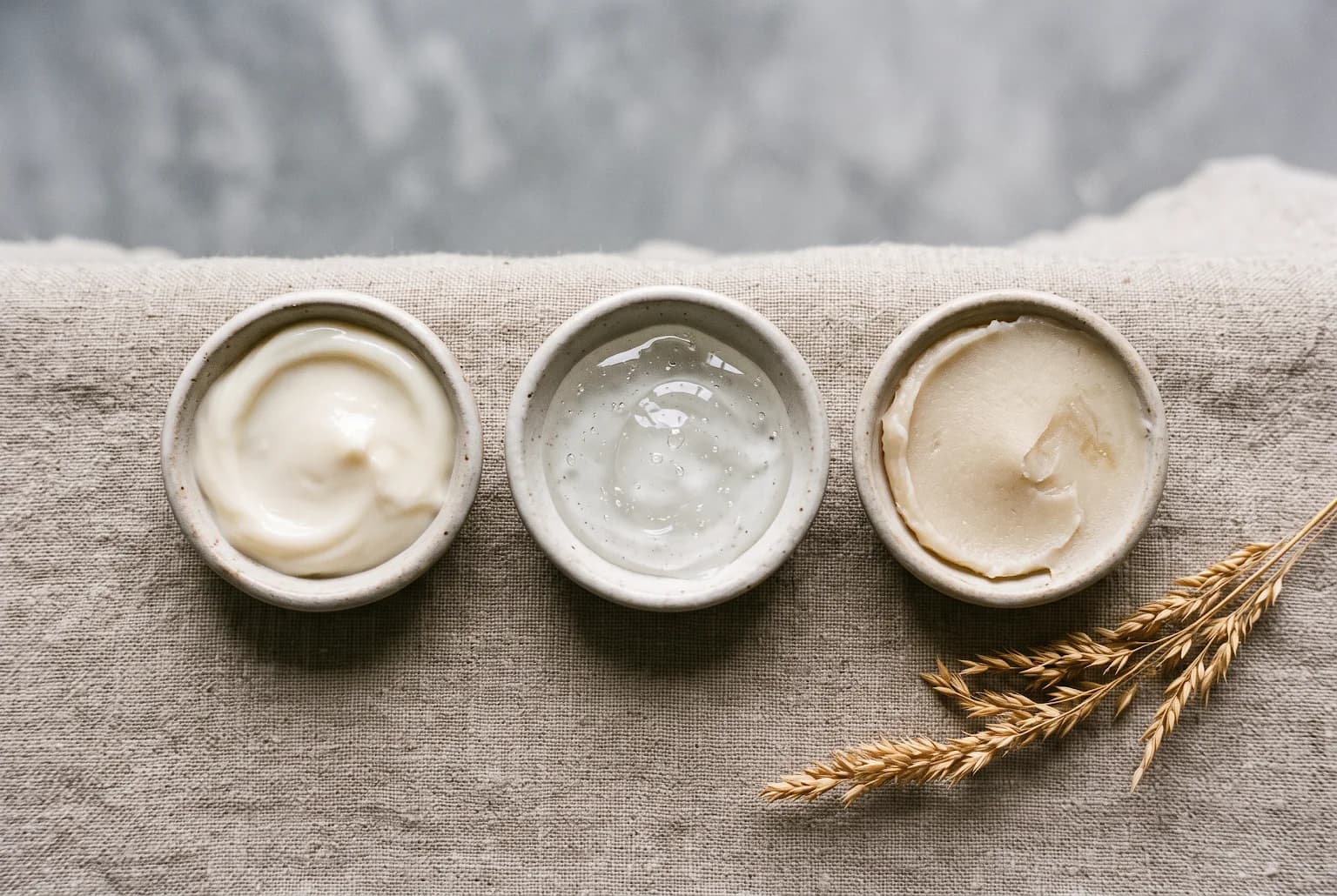 Three cleanser textures in small dishes: cream, gel, balm.