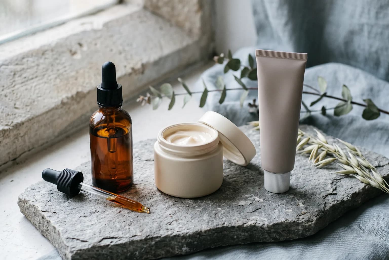 Antioxidant serum, peptide moisturizer, and SPF tube on a stone slab
