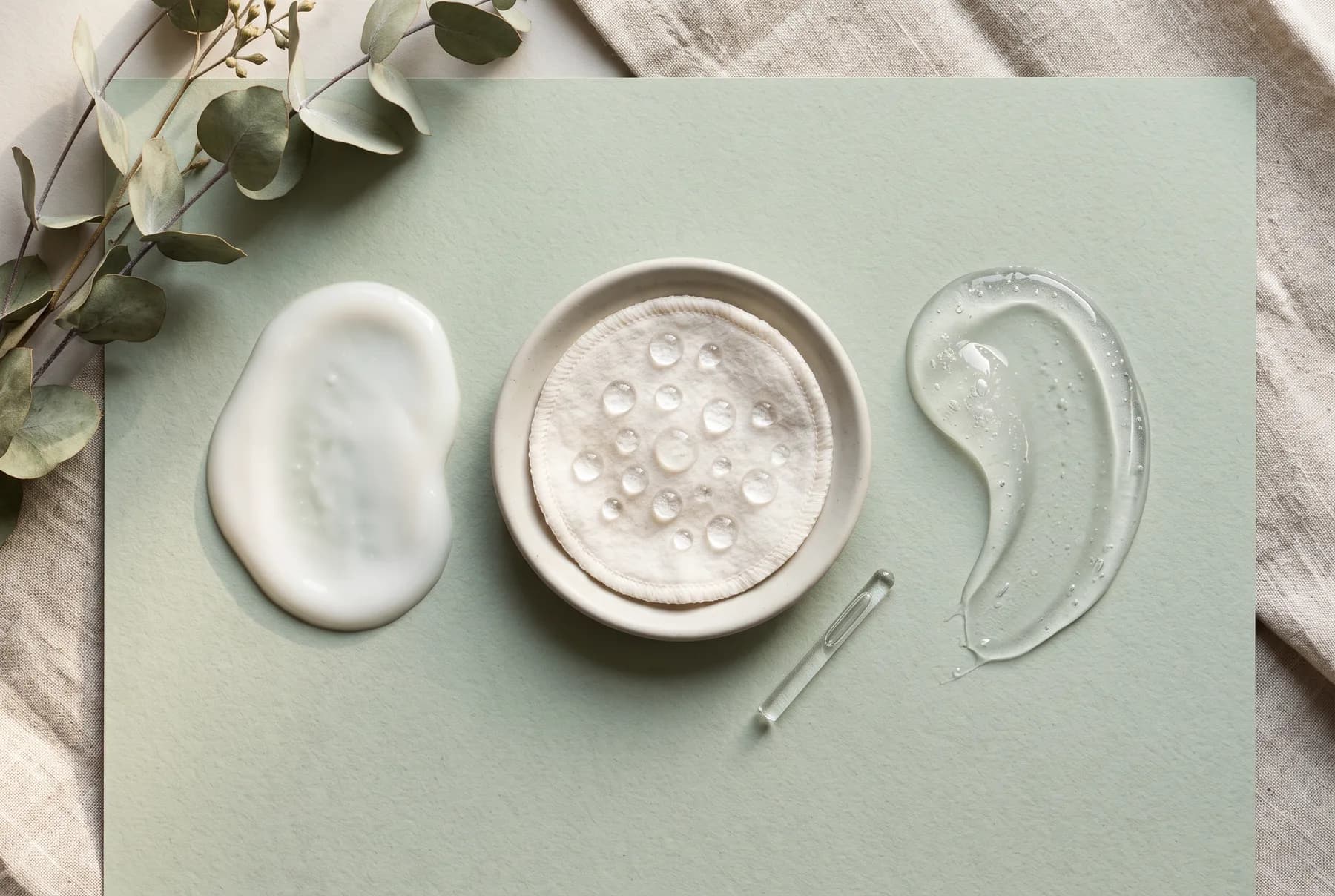 Cream, micellar water, and clear gel cleanser textures arranged on a pale green surface