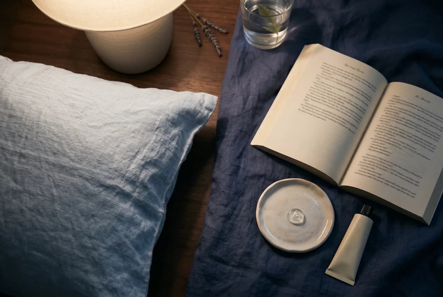 Nighttime still life with a pea-sized gel texture on a ceramic palette beside bedding